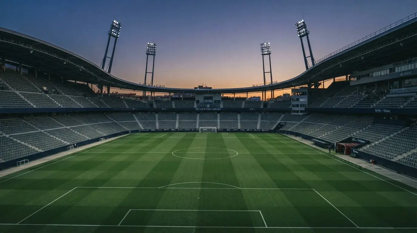Een leeg voetbalstadion met lichtmasten bij schemering