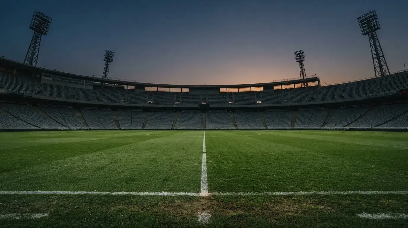 Een leeg voetbalstadion met lichtmasten bij schemering