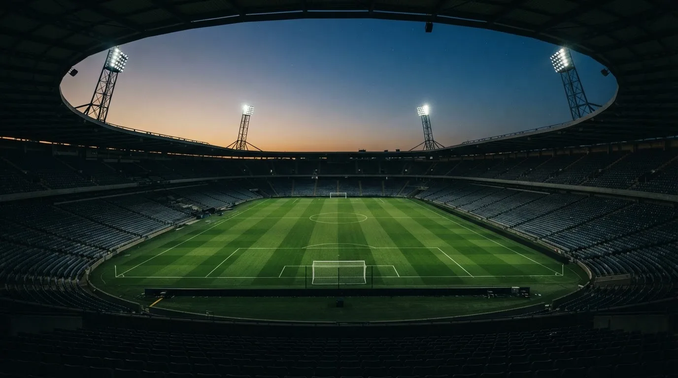 Een leeg voetbalstadion met lichtmasten bij schemering