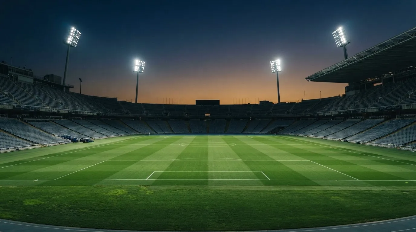 Een leeg voetbalstadion met lichtmasten bij schemering