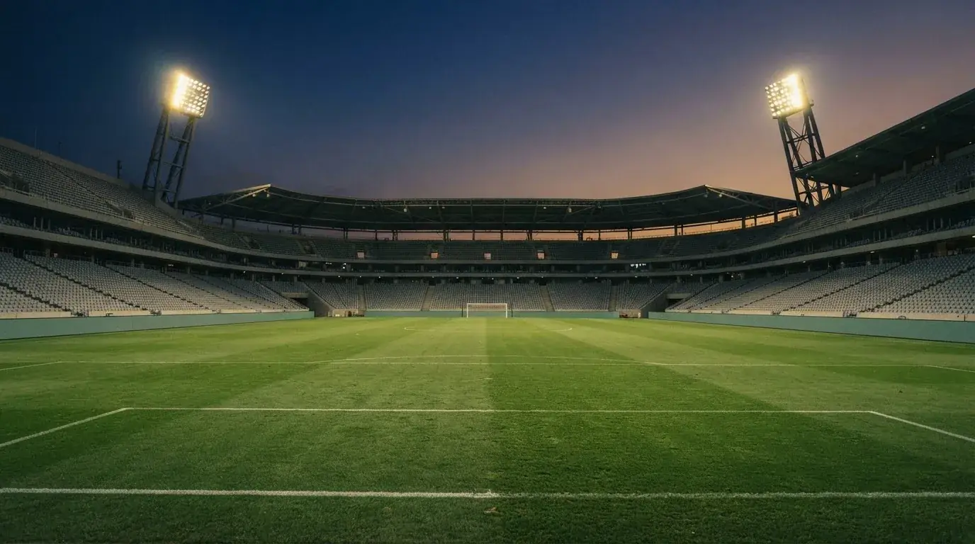 Een leeg voetbalstadion met lichtmasten bij schemering