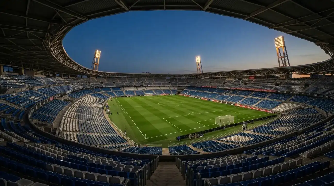 Een leeg voetbalstadion met lichtmasten bij schemering