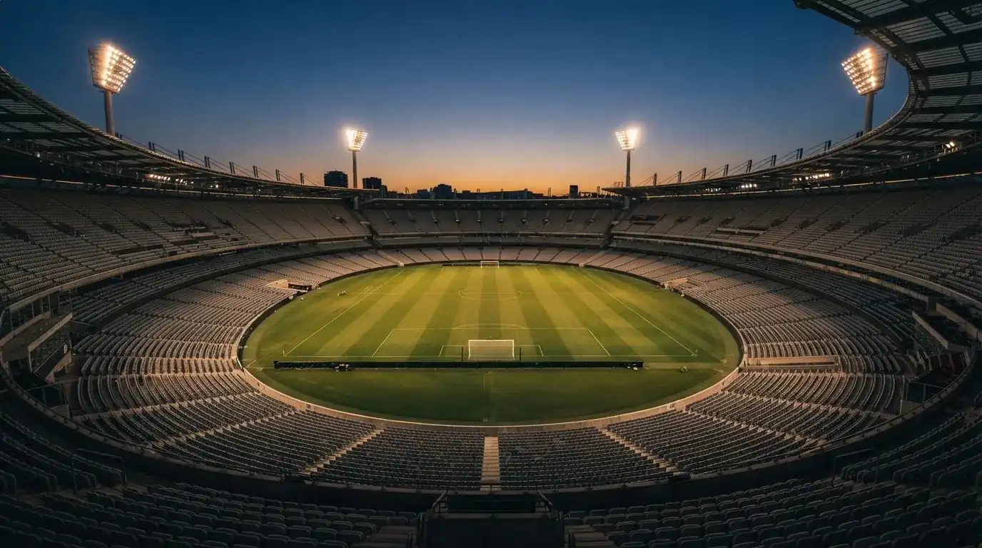 Een leeg voetbalstadion met lichtmasten bij schemering