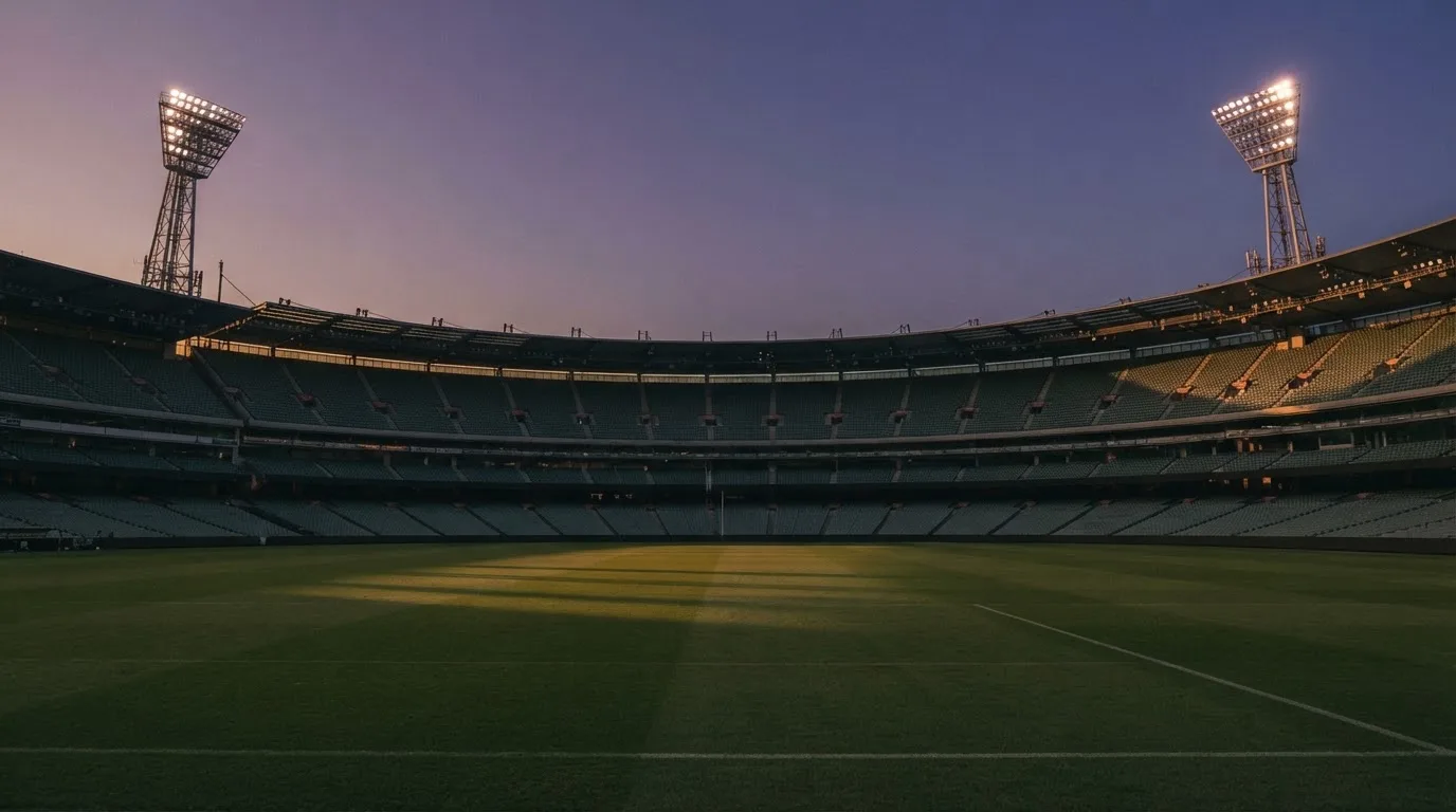 Een leeg voetbalstadion met lichtmasten bij schemering