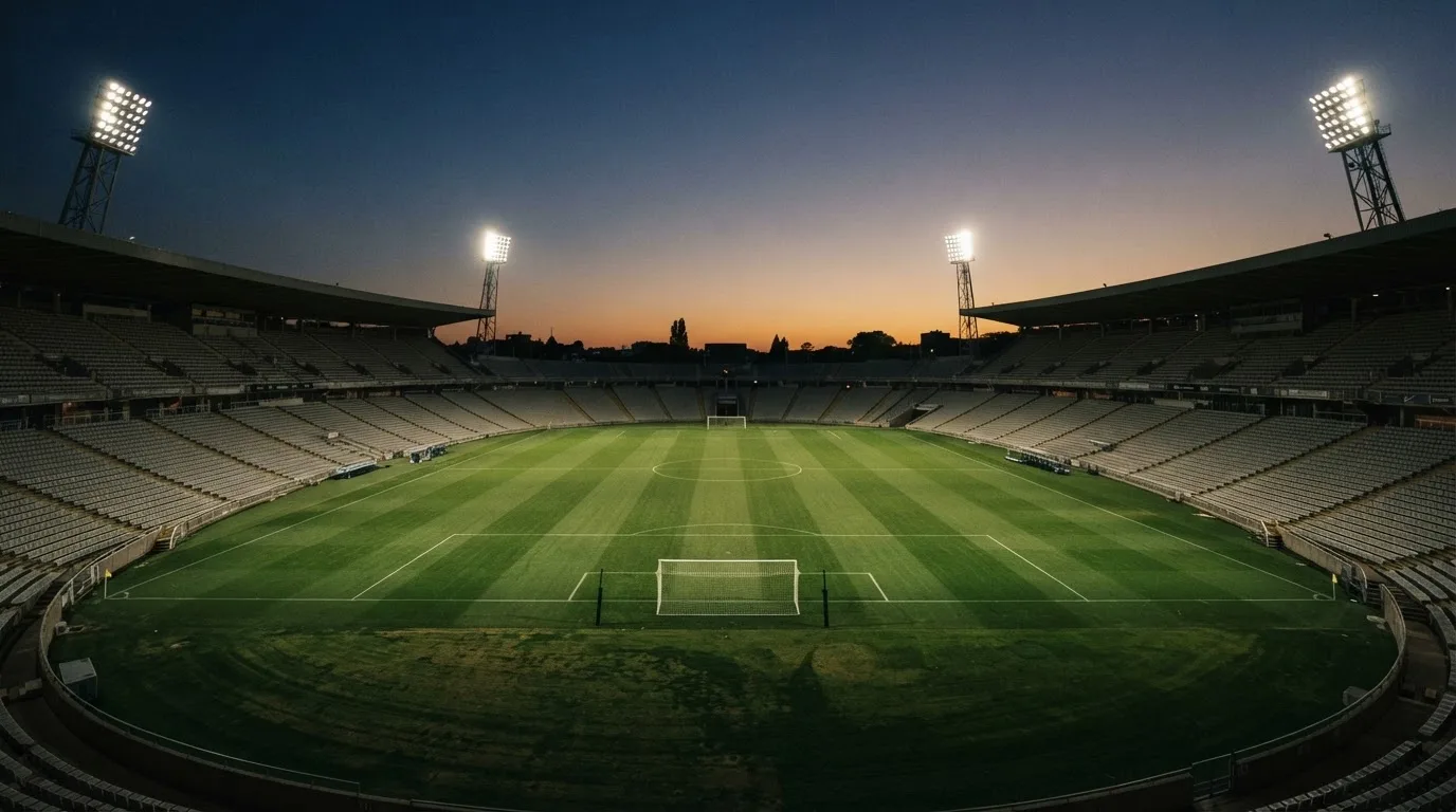 Een leeg voetbalstadion met lichtmasten bij schemering