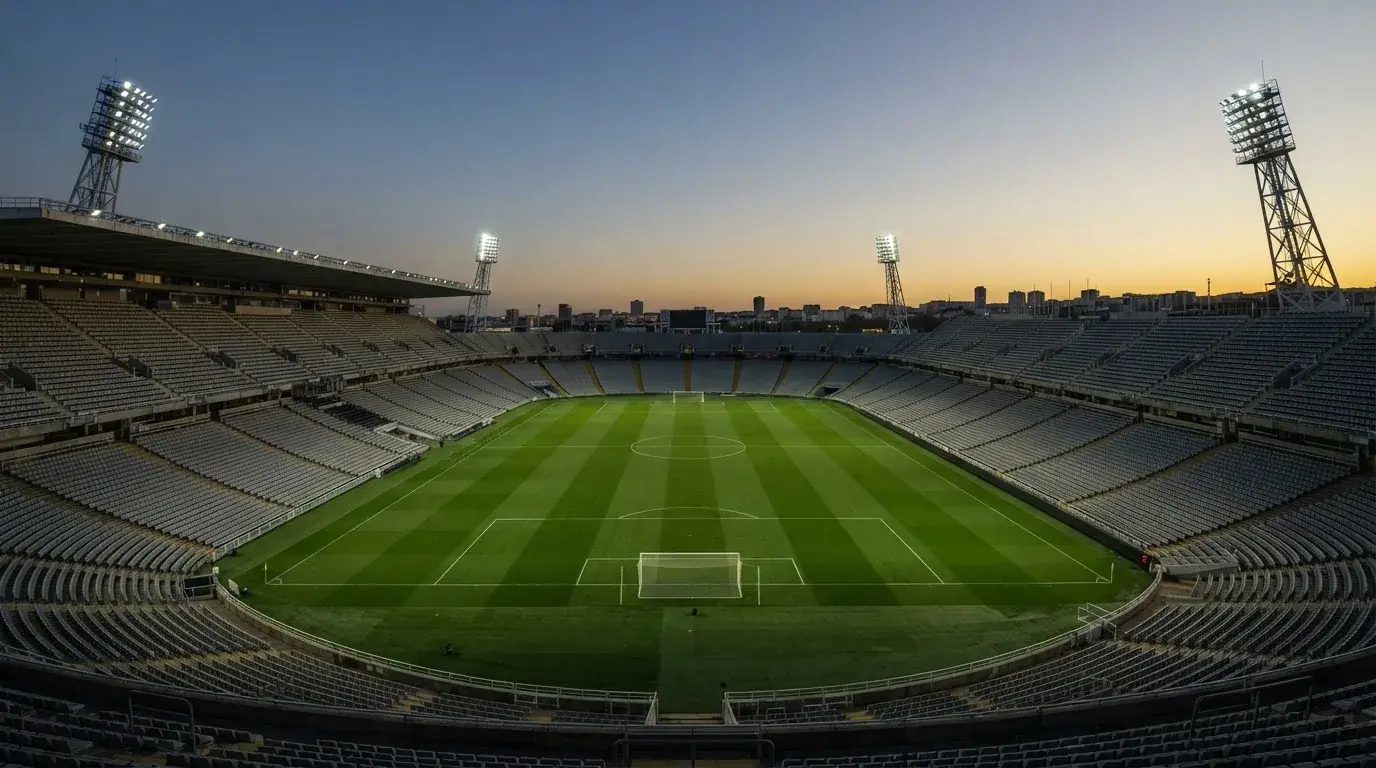 Een leeg voetbalstadion met lichtmasten bij schemering
