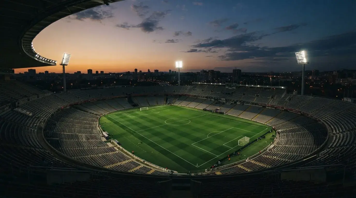 Een leeg voetbalstadion met lichtmasten bij schemering