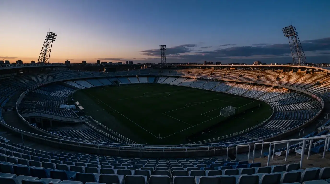 Een leeg voetbalstadion met lichtmasten bij schemering